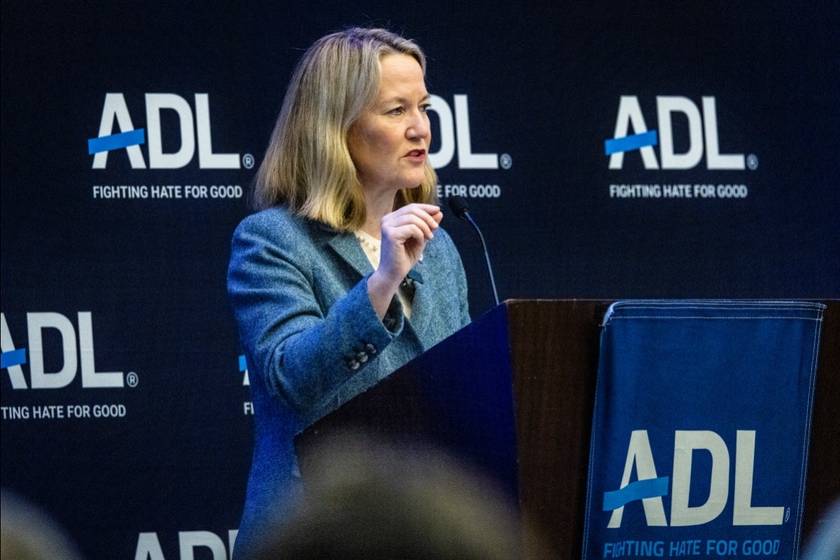 Woman speaks to audience from lectern with an ADL background behind her