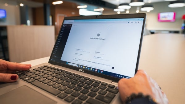 Hands sit on an open laptop with a screen that says How can I help you today?