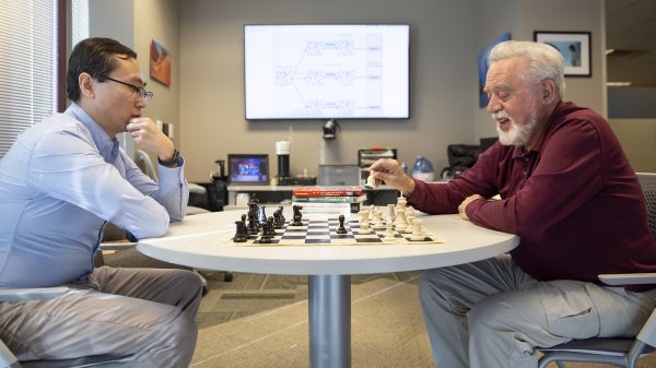 Yuchao Li and Dimitri Bertsekas play chess.