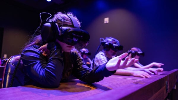 Young girl wearing a VR headset reaches out her hand in front of her.