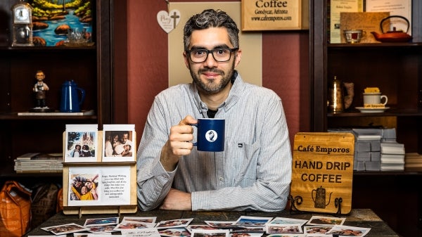 A man sits at a table holding a coffee cup