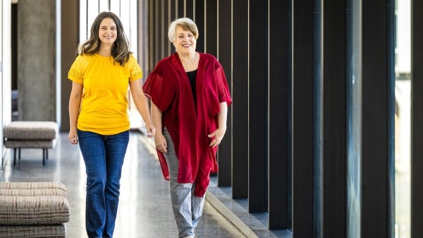 A mother-daughter teaching due walk down hall
