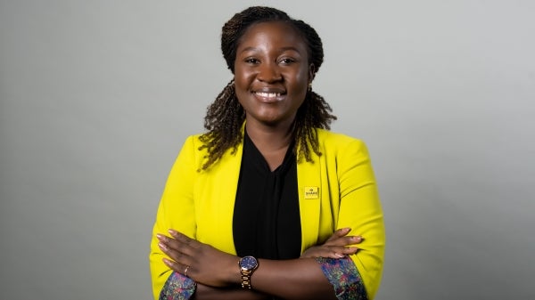 Aisha Ndahi poses for her profile photo in a yellow blazer with aa black v-neck shirt