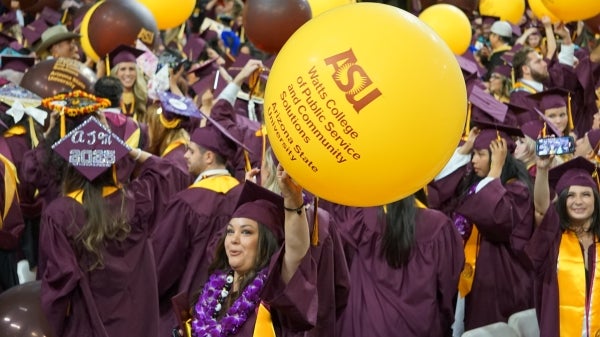 A large group of grads under falling balloons
